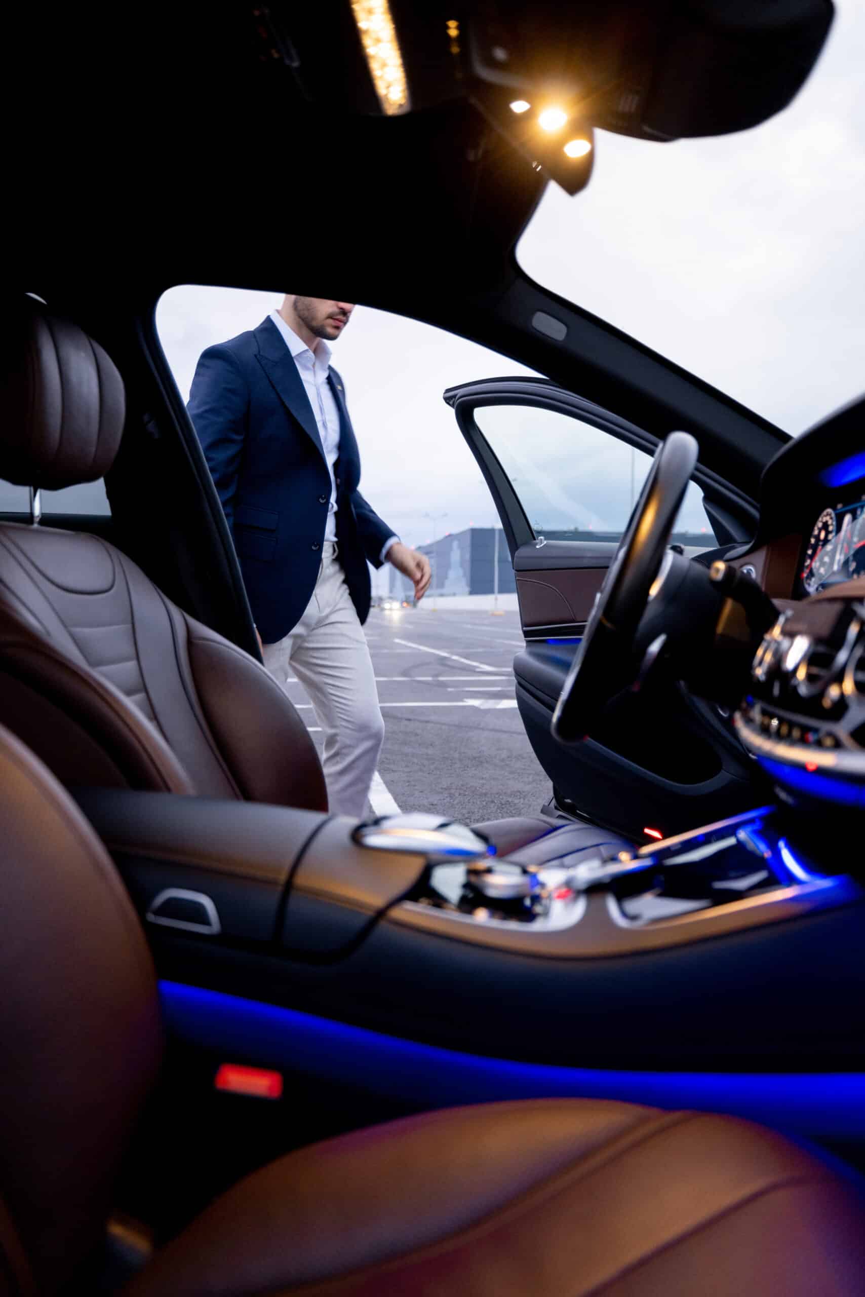 Businessman get in luxury car, view from vehicle interior. Business transportation and lifestyle